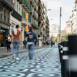 Pla general de dos homes caminant pel carrer Pelai, amb l'espai per a vianants pintat amb panots blaus, en una imatge d'arxiu