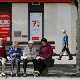 Varios pensionistas sentados en un banco cerca de una oficina bancaria en la localidad burgalesa de Briviesca. AFP / César Manso