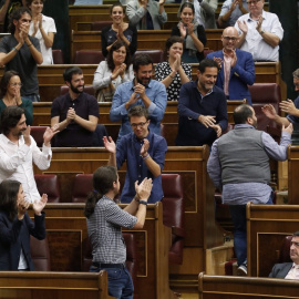 Joan Mena, de espaldas, sube a su escaño entre los aplausos de Podemos. / EFE