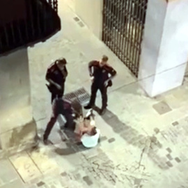 Captura del vídeo del moment en què l'agent dels mossos venta una bufetada a l'home assegut al mig del carrer a Olot