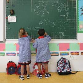 Dos niños pintan en una pizarra el día de inicio del curso en el colegio de la Alameda de Osuna, a 5 de septiembre de 2022, en Madrid (España).