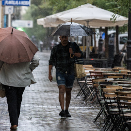 Varias personas se resguardan de la lluvia con paraguas, a 3 de septiembre de 2023, en Madrid