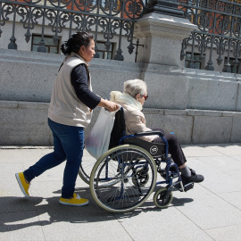 Una mujer mayor en silla de ruedas y su cuidadora pasean por el centro de la ciudad, a 4 de junio de 2023, en Madrid.