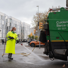 Una trabajadora de la limpieza riega una calle con una manguera en Barcelona, Catalunya.