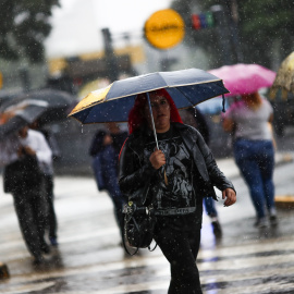 Una mujer cruza un paso de peatones durante una fuerte tormenta, en el centro de Buenos Aires (Argentina). EFE/David Fernández