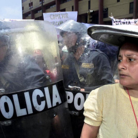 Una mujer de la organización popular Madres del Vaso de Leche se cubre la cabeza con la tapa de una olla el 27 de noviembre de 2003 en las puertas del Congreso en Lima.