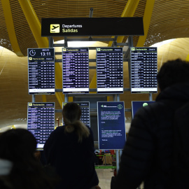 Varias personas comprueban los paneles de información tras el fallo de conectividad en los sistemas de Iberia.