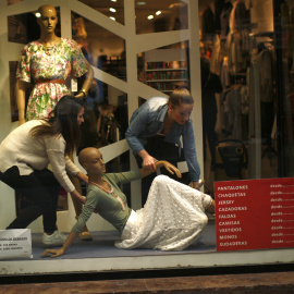 Un par de empleados arreglan el escaparate de una tienda en el centro de Madrid. REUTERS