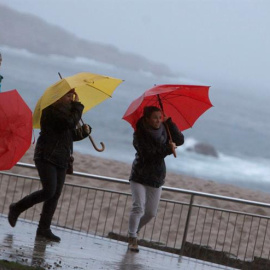 Tres mujeres se protegen de la lluvia en el paseo marítimo de A Coruña. - EFE