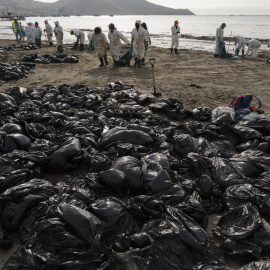 Equipos de limpieza trabajan para retirar petróleo de una playa anexa al balneario de verano de Ancón, en el norte de Lima, el 20 de enero de 2022.