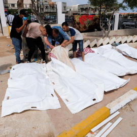 Varias personas buscan entre los cadáveres a familiares y conocidos tras el paso devastador del ciclón Daniel por la ciudad de Derna, en Libia.