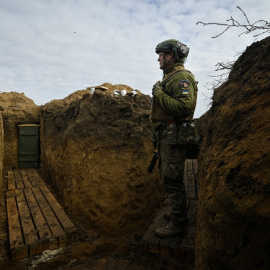 Un soldado ucraniano observando tras una trinchera.