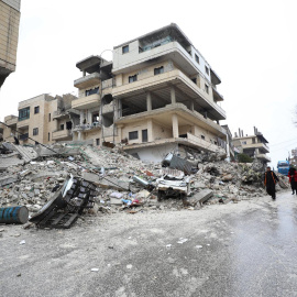 Gente camina al lado de varios edificios derrumbados por el terremoto en la ciudad de Armanaz, en el distrito de Idlib (Siria) este 6 de febrero de 2023.