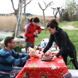 Pla general d'un grup d'amics preparant la taula amb la mona que han elaborat ells mateixos, al costat de l'embassament de Sant Llorenç de Montgai