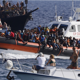 Migrantes rescatados llegan en un barco al puerto de Lampedusa entre dos barcos de turistas, a 18 de septiembre de 2023.