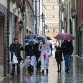 Varias personas caminando bajo la lluvia en Teruel, a 31 de marzo de 2024