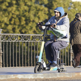 Una persona en su patinete, en Puente de Triana, en Sevilla.