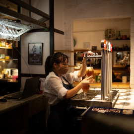 Una camarera sirve una cerveza en el interior de un bar en una calle céntrica de Barcelona