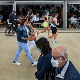 Varias personas pasean frente a un chiringuito del Paseo Marítimo de la Barceloneta hoy domingo, durante el primer día sin toque de queda en Cataluña,