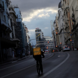 Un repartidor circula en bicicleta por la Gran Vía de Madrid, que permanece prácticamente sin coches debido a la crisis del coronavirus. Reuters/Susana Vera