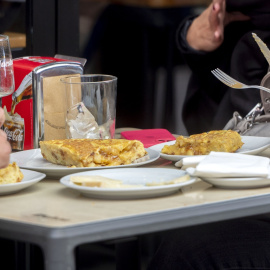 Imagen de archivo de dos personas en un bar con dos tapas de tortilla de patatas.