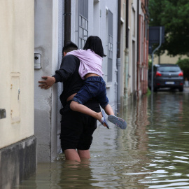 Un hombre y una niña abandonan su vivienda tras las fuertes inundaciones en la región de Emilia Romaña, en el noreste de Italia.