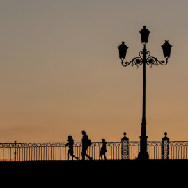 Un padre con sus hijos pasando al atardecer por el Puente de Triana, a 28 de abril del 2020, en Sevilla, Andalucía.