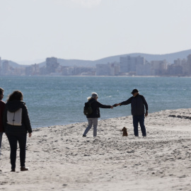 Varias personas disfrutan de las agradables temperaturas registradas este viernes, en la playa de Saler de València.