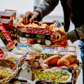 Una persona coge una caja de fresas en la frutería 'Vitaminas', a 2 de enero de 2023, en Madrid (España).