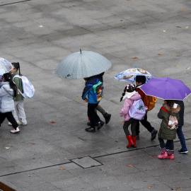 Varios niños se dirigen al colegio con botas y paraguas debido a la lluvia, en Bilbao, a 21/11/2023