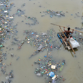 buscando productos de plástico reciclado en el canal lleno de desechos plásticos