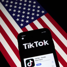 Un móvil con la aplicación China TikTok, sobre una bandera de EEUU.