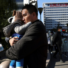 Un hombre con su hijo a las puertas de un hospital en Pekín, China, este 24 de noviembre de 2023.