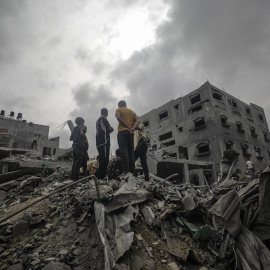 Algunas personas buscan cadáveres y supervivientes entre los escombros de una casa destruida tras un ataque aéreo israelí en el campo de refugiados de Al Nusairat, sur de la Franja de Gaza, el 27 de abril de 2024.