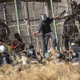 Un agente marroquí golpea desde territorio español con un palo a los migrantes que lograron saltar la valla de Melilla el pasado viernes.