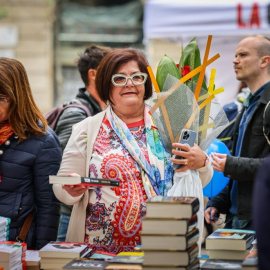 Una dona amb una rosa i el llibre de Carles Porta en una parada al centre de Barcelona per Sant Jordi