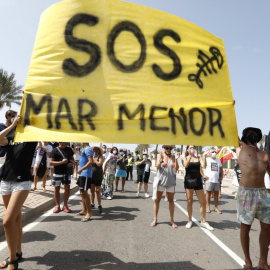 Varias personas participan en una protesta en defensa del Mar Menor al paso de la Vuelta Ciclista a España, a 21 de agosto de 2021, en La Manga.