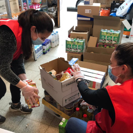 Dues voluntàries de Creu Roja preparen lots d'aliments.