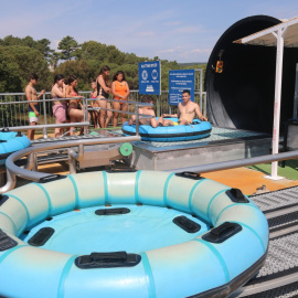 Visitants fent cua i altres ja en un matalàs inflable en una atracció del parc aquàtic Waterworld, a Lloret de Mar.