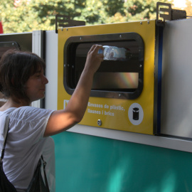 Una dona llençant una ampolla de plàstic a una plataforma de recollida selectiva mòbil al barri de Bon Pastor de Barcelona.