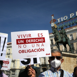 Un grupo de personas se reúne sosteniendo pancartas y carteles durante la concentración de la asociación Derecho a Morir Dignamente en la Puerta del Sol, a 25 de junio de 2021, en Madrid, (España)