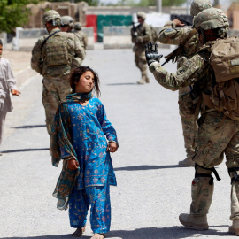 Unos niños pasan al lado de soldados estadounidenses en Afganistan.