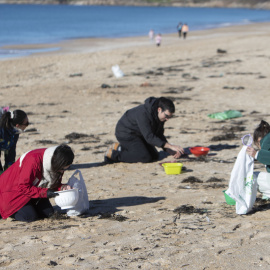 Voluntarios recogen microeplásticos o pellets, que han aparecido en toda la costa atlántica de Galicia, este domingo en la Playa de A Lanzada en O Grove.