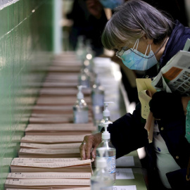 04/05/2021.- Una mujer escoge una papeleta para ejercer su derecho al voto en el colegio La Inmacualada-Marillac en Madrid durante la jornada electoral.