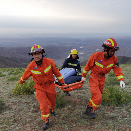 Equipos de emergencia llevan una camilla en las operaciones de búsqueda de 21 atletas que fallecieron en una carrera de montaña.