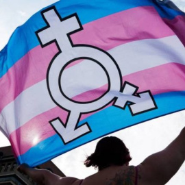 Una persona ondea una bandera trans.