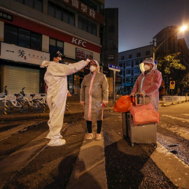 Un voluntario toma la temperatura a una mujer embaraza en la ciudad china de Wuhan. - EFE