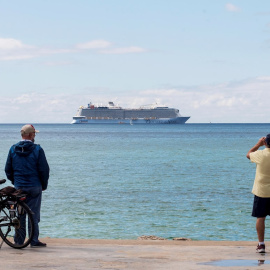 Unos hombres observan el crucero turístico "Odissey of the Seas" fondeando este lunes en la bahía de Palma de Mallorca.