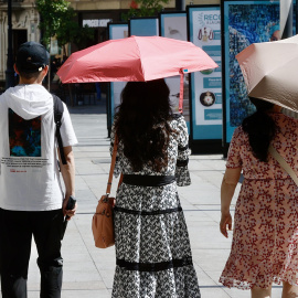 Varios turistas se cubren del sol con sombrillas mientras pasean este martes por Sevilla.