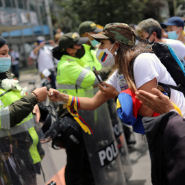 Una mujer golpea los puños con un oficial de policía mientras la gente marcha en oposición a los bloqueos de carreteras y la violencia después de un mes de protestas nacionales, en Bogotá, Colombia.